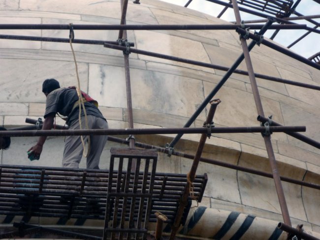  A worker cleans a portion of the Taj Mahal complex. Marble on the right shows brownish discoloration caused by particles of carbon, and dust. Credit: Mike Bergin.